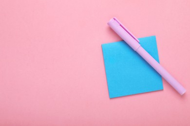 Paper note and purple marker on pink background, top view. Space for text