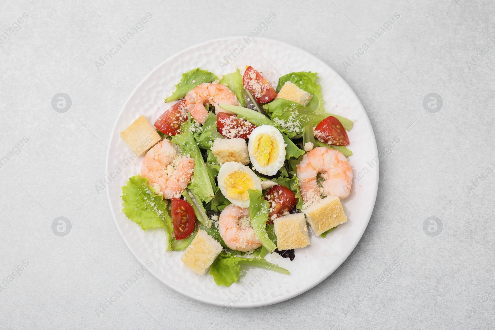 Photo of Delicious Caesar salad with shrimps on light table, top view