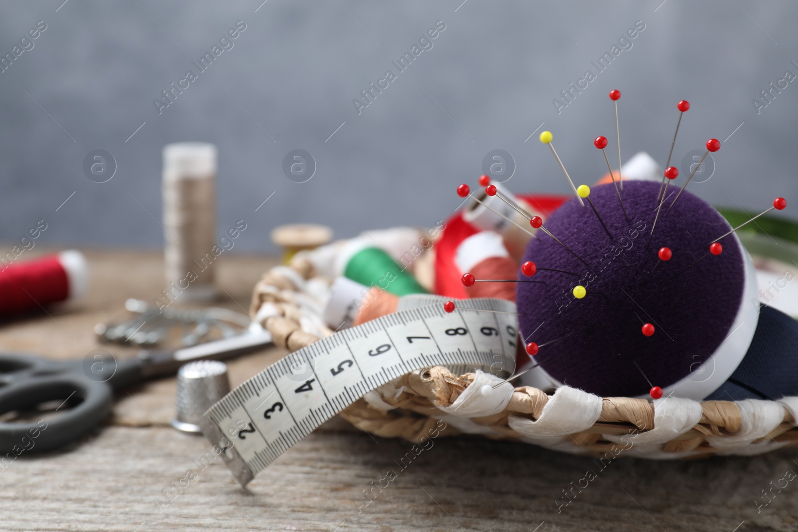 Photo of Blue pincushion with pins and other sewing tools on wooden table