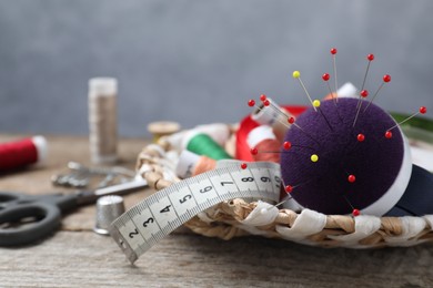 Blue pincushion with pins and other sewing tools on wooden table