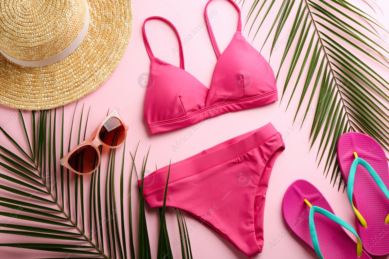 Photo of Beautiful bikini and beach accessories on pink background, flat lay