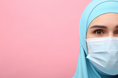 Photo of Muslim woman in hijab and medical mask on pink background, closeup. Space for text