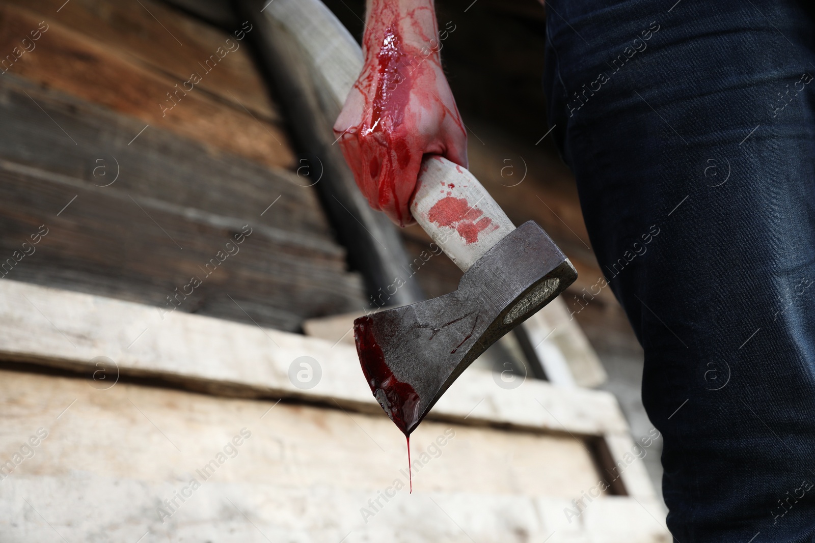 Photo of Man holding bloody axe outdoors, closeup. Space for text