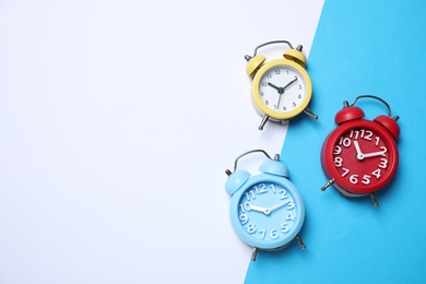 Photo of Modern alarm clocks on color background, flat lay. Space for text