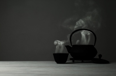 Photo of Oriental teapot and cup on table against grey background, space for text