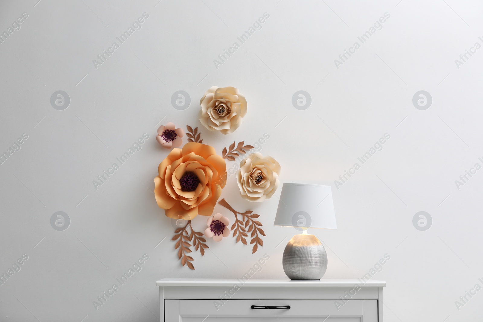 Photo of Stylish room interior with floral decor, table and lamp