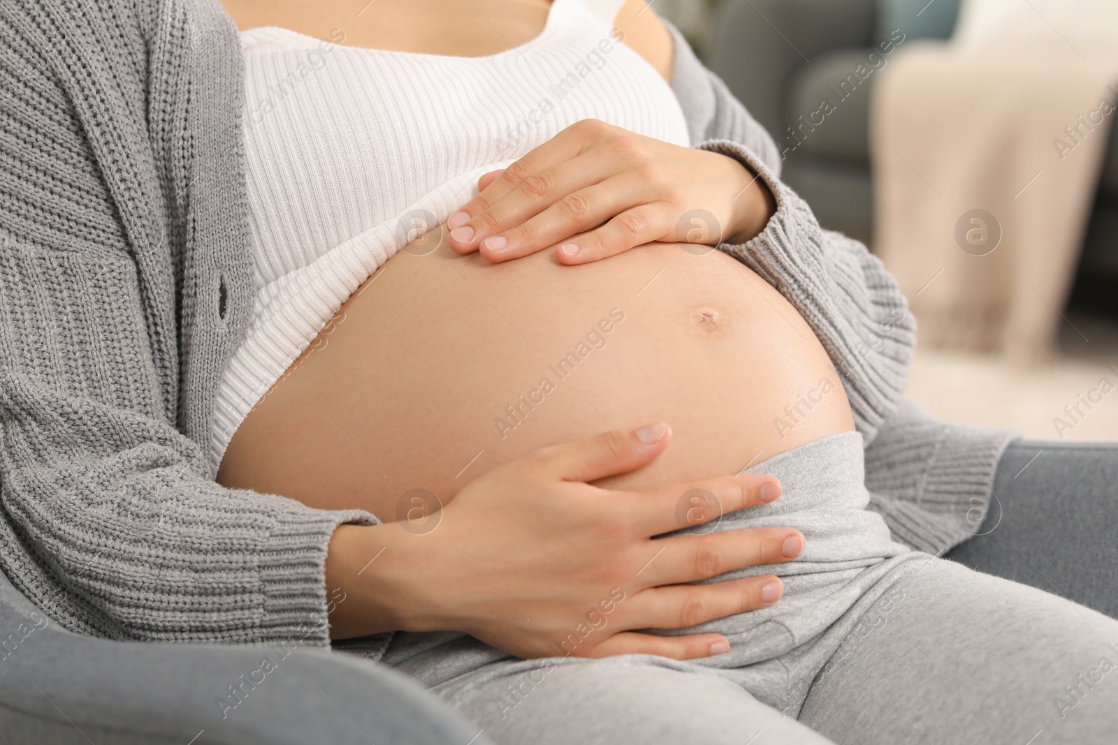 Photo of Pregnant woman sitting in armchair at home, closeup