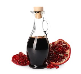 Photo of Glass jug of pomegranate sauce and fresh ripe fruit on white background