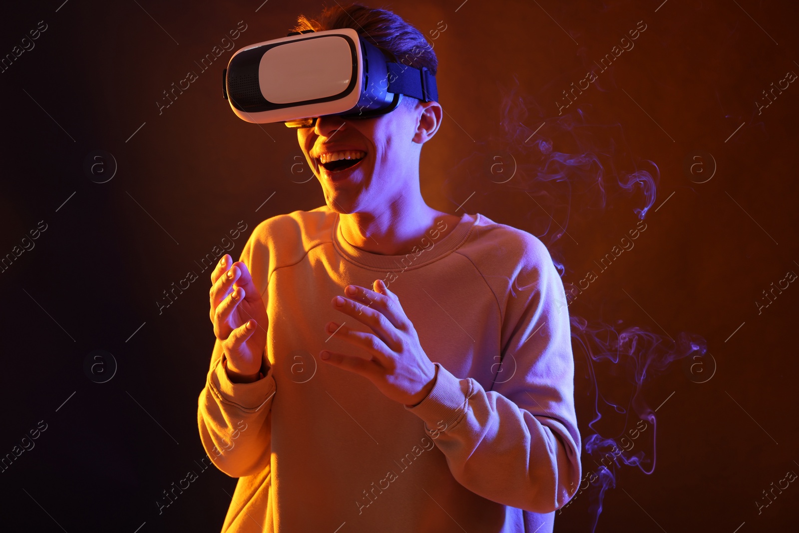 Photo of Young man with virtual reality headset on brown background