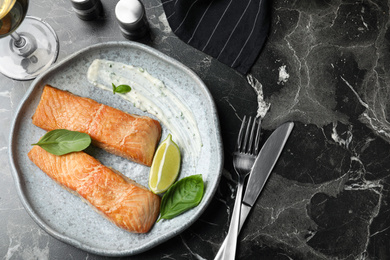 Photo of Tasty cooked red fish on dark marble table, flat lay
