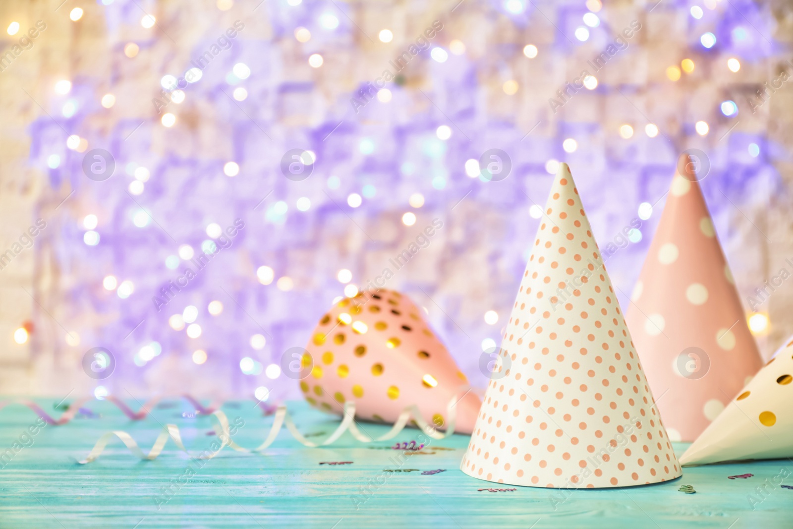 Photo of Birthday party caps on table against blurred lights