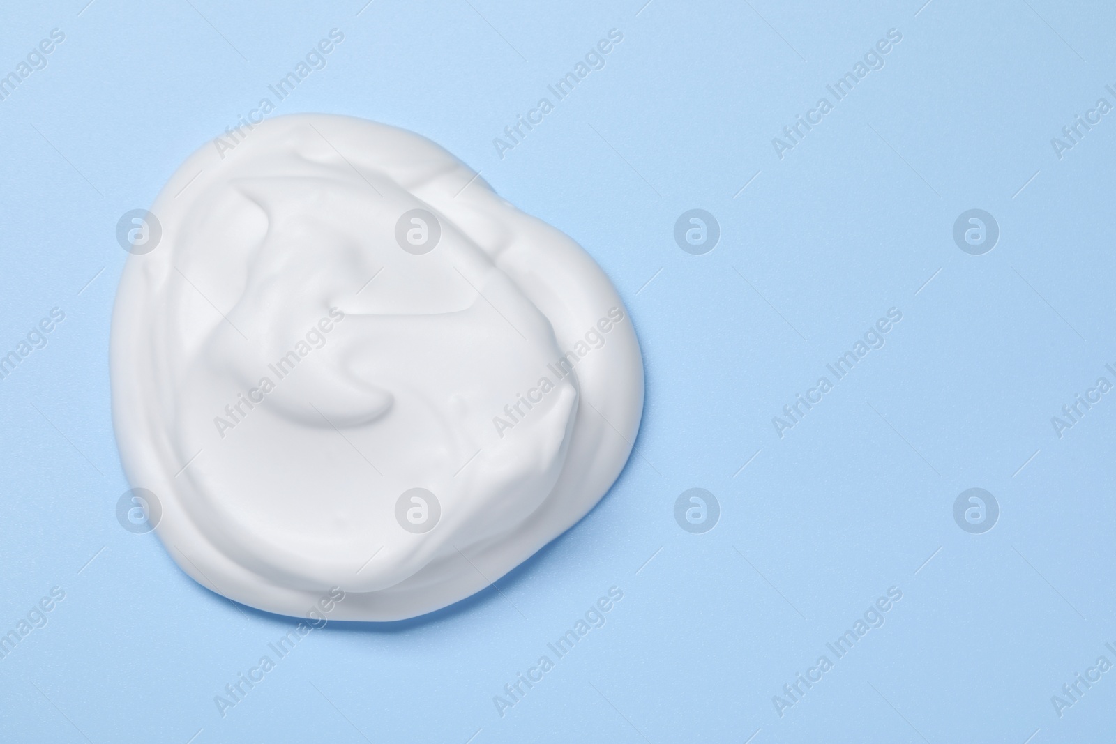 Photo of Sample of shaving foam on light blue background, top view. Space for text