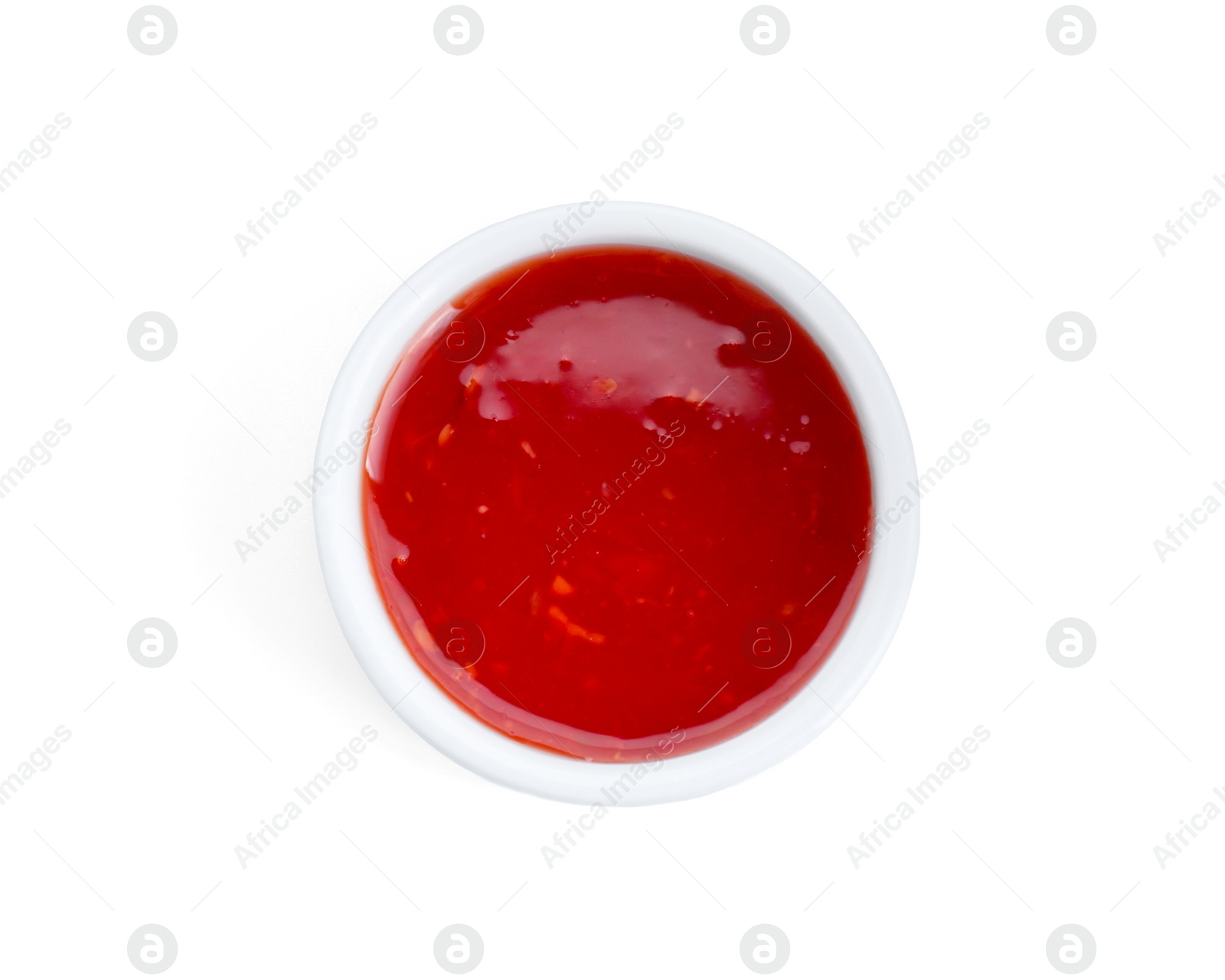 Photo of Spicy chili sauce in bowl isolated on white, top view