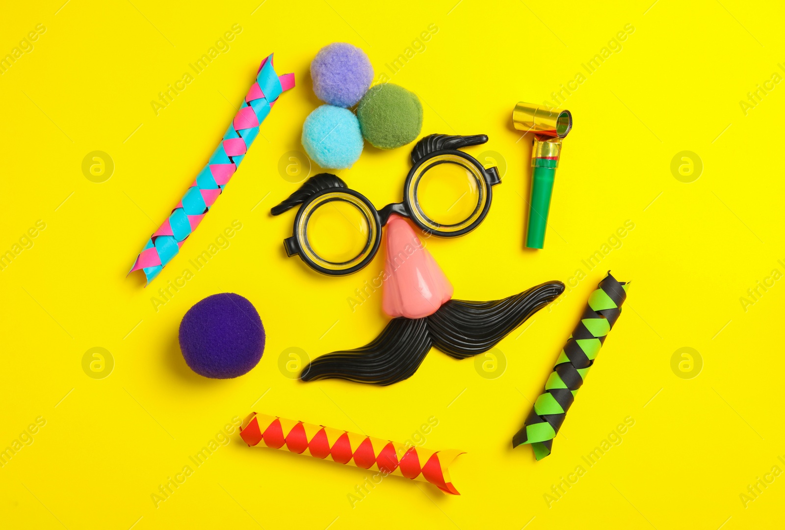 Photo of Funny face made with clown's accessories on yellow background, flat lay