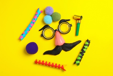 Funny face made with clown's accessories on yellow background, flat lay