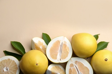 Photo of Fresh cut and whole pomelo fruits with leaves on beige background, flat lay. Space for text