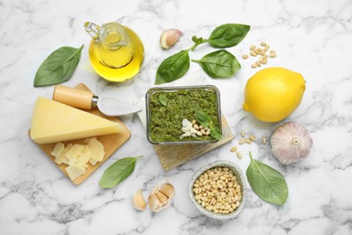 Flat lay composition with delicious pesto sauce and ingredients on white marble table