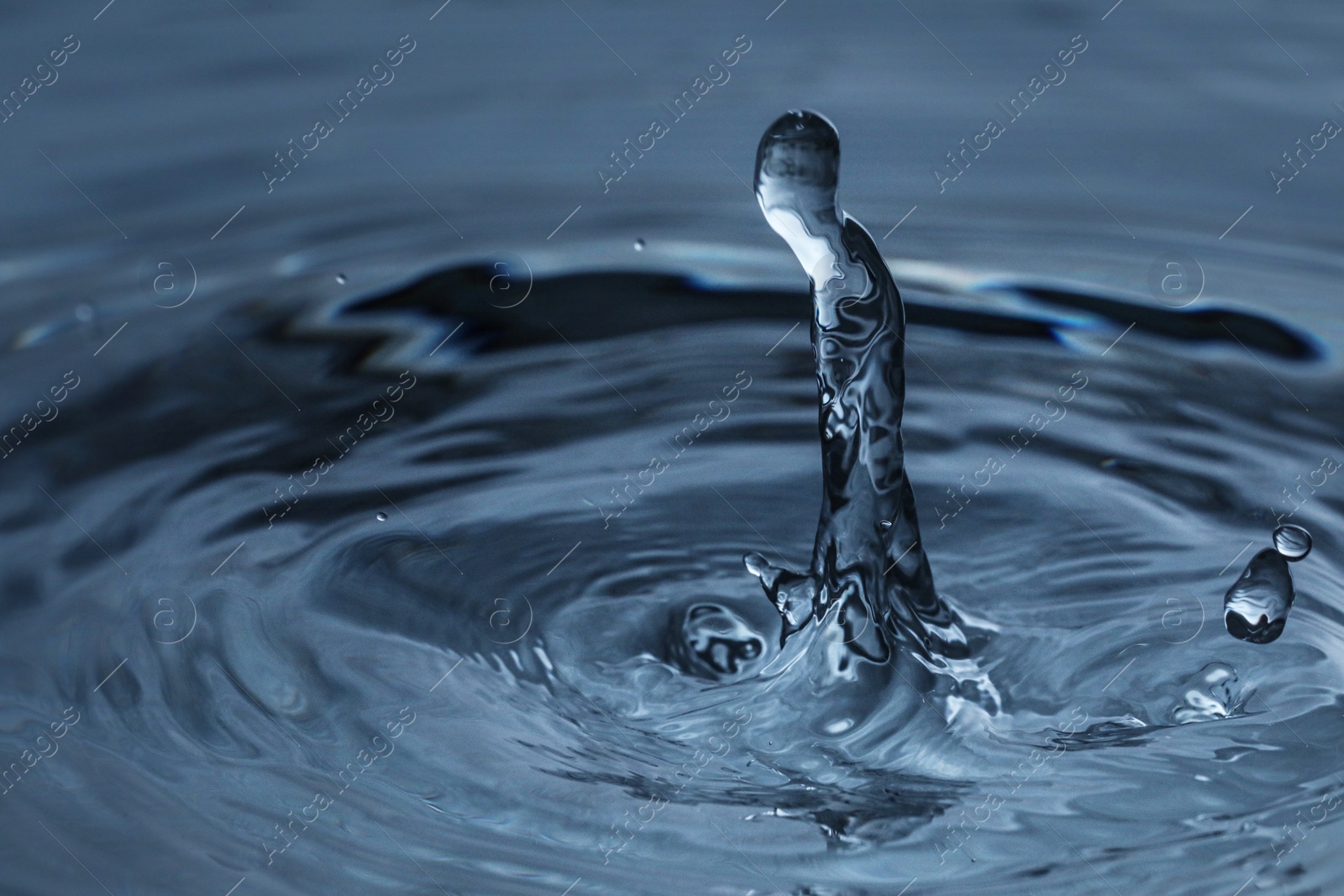 Photo of Splash of clear water with drops on dark blue background, closeup