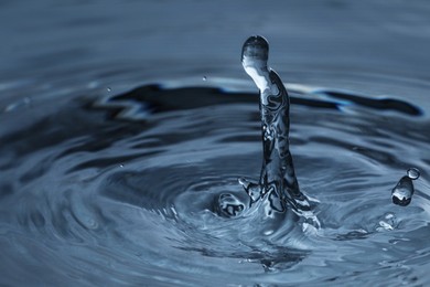 Photo of Splash of clear water with drops on dark blue background, closeup