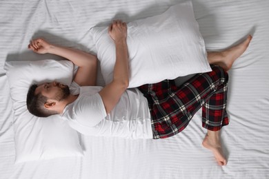 Man suffering from insomnia on bed, top view