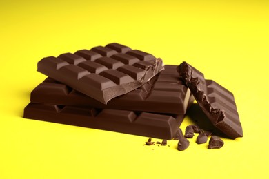 Photo of Delicious dark chocolate bars on yellow background