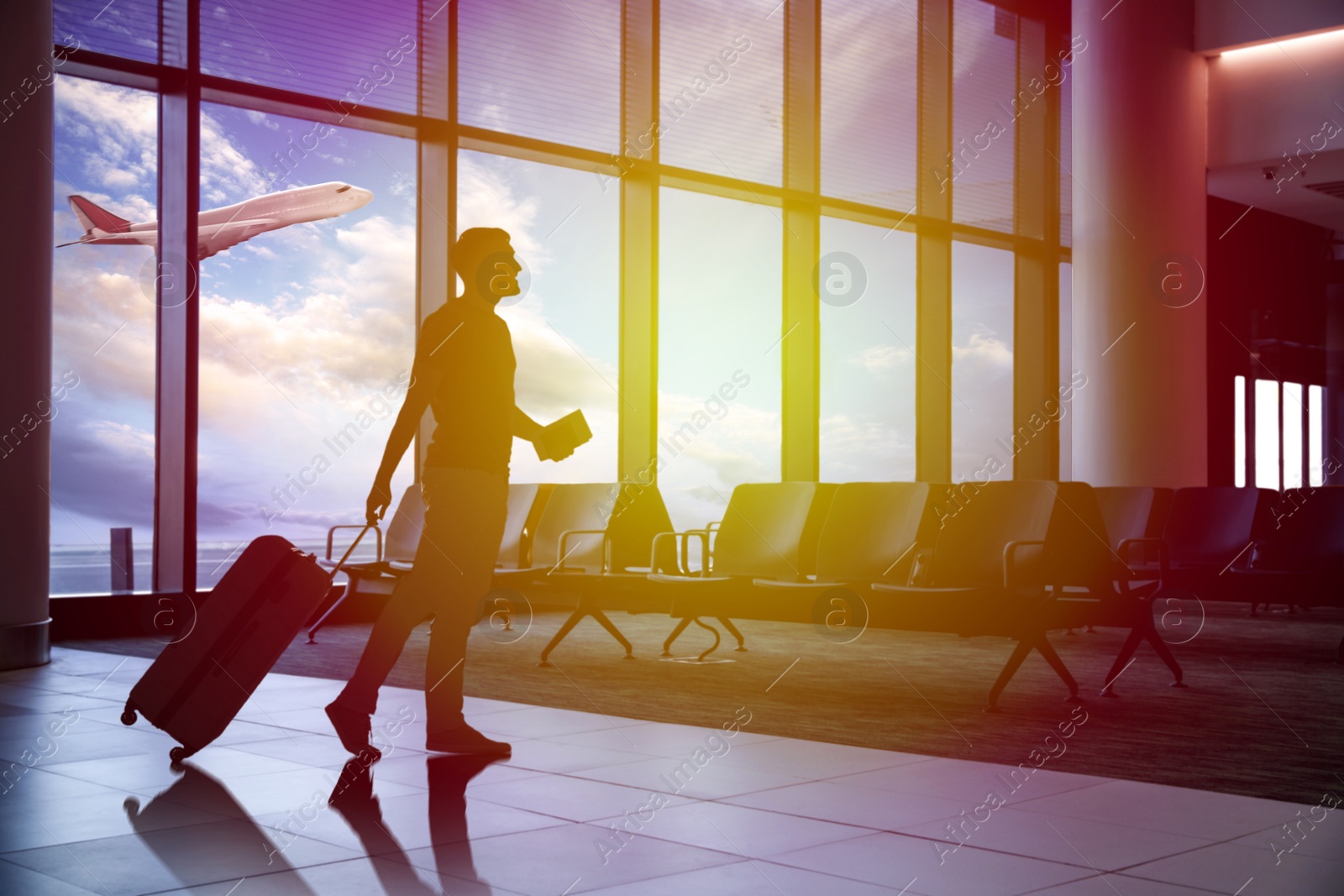 Image of Silhouette of man with suitcase in airport