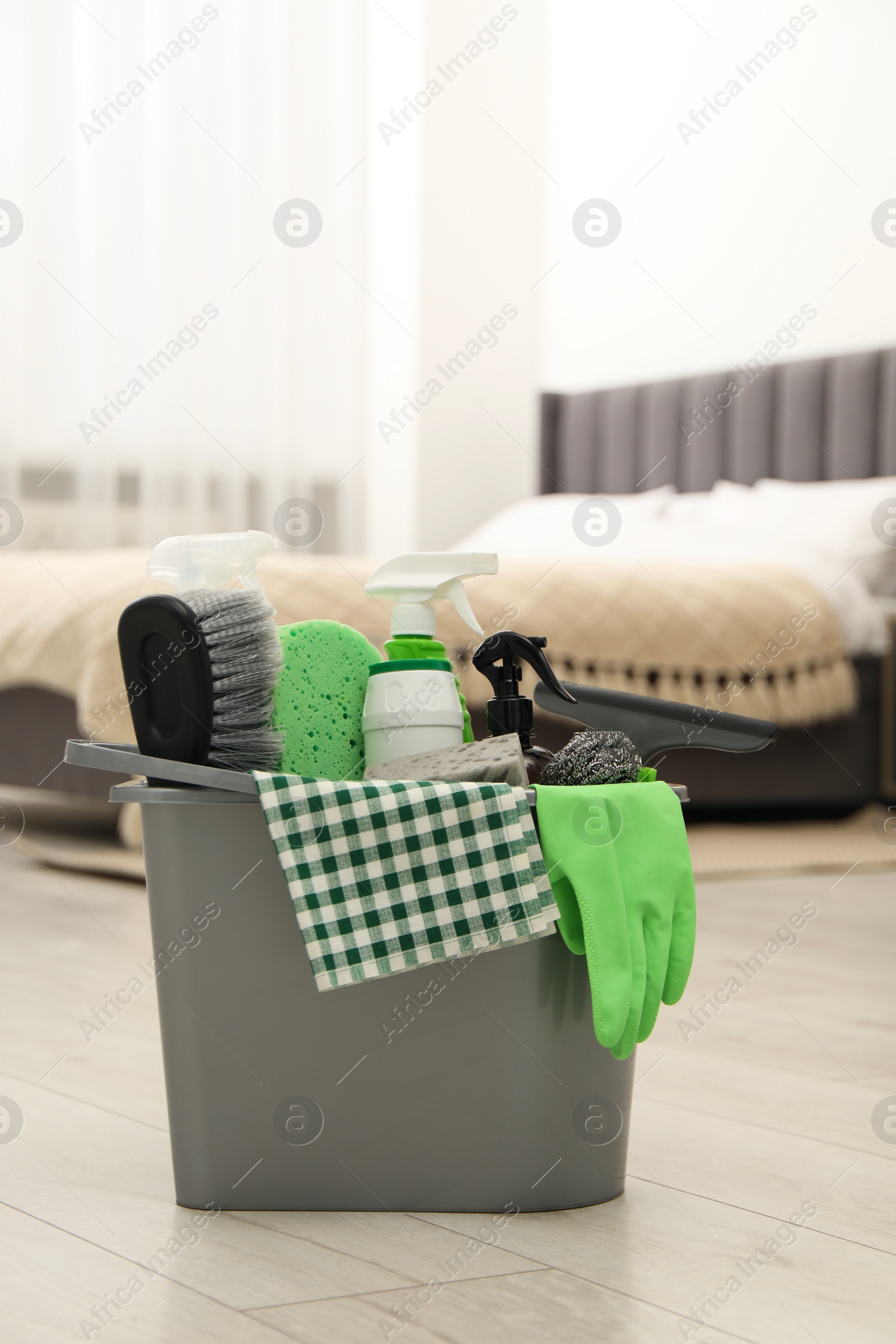 Photo of Different cleaning supplies in bucket on floor at home