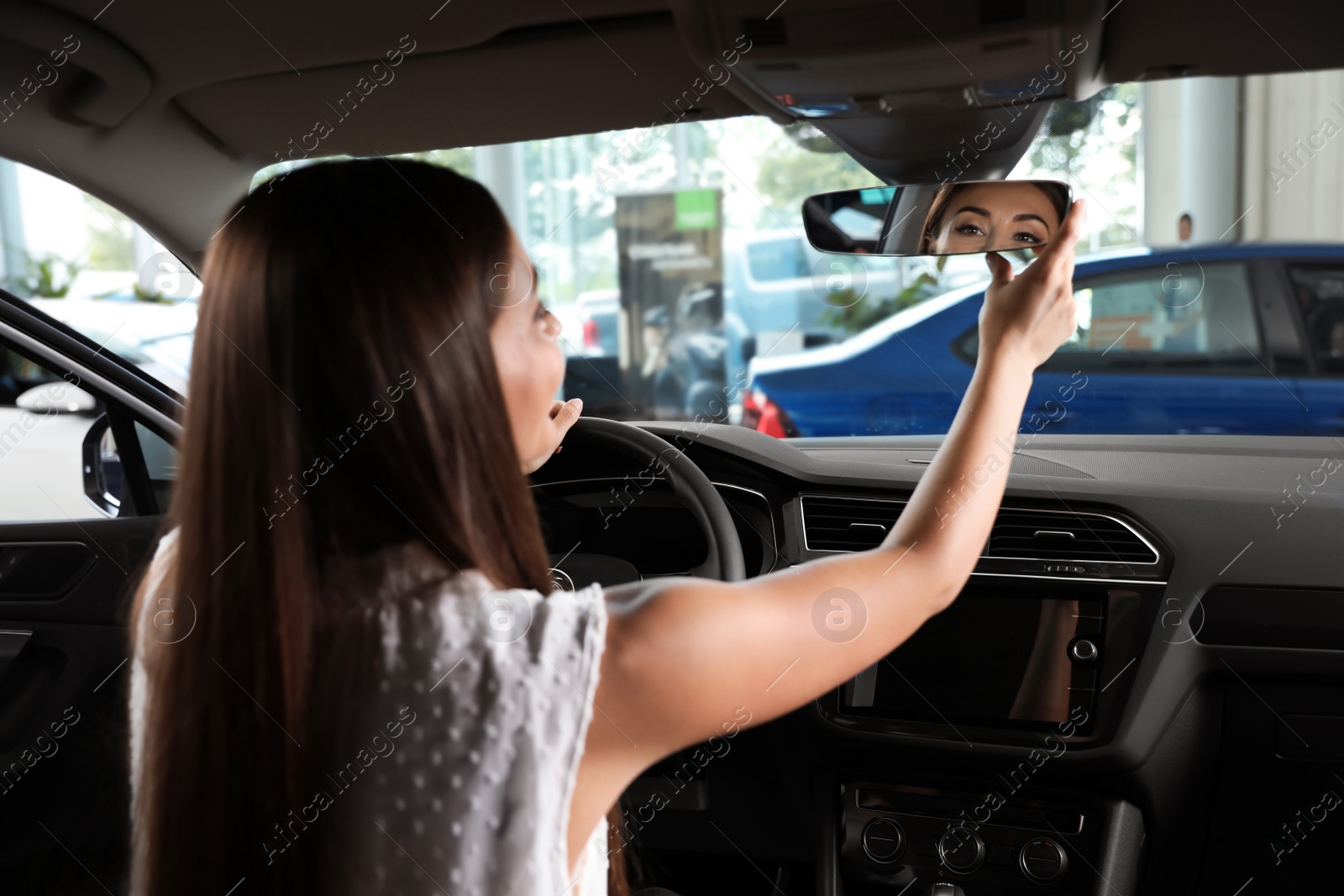 Photo of Young woman testing new car in salon