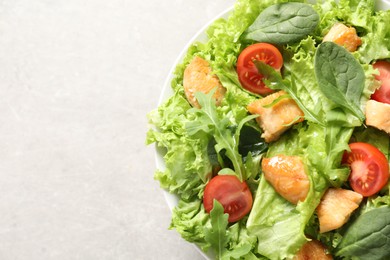 Delicious salad with chicken, cherry tomato and spinach on light grey table, top view. Space for text