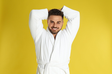 Photo of Happy young man in bathrobe on yellow background