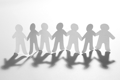 Photo of Paper people holding hands on white background. Unity concept