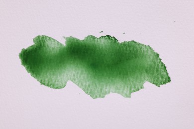 Photo of Blot of green watercolor paint on white paper, top view