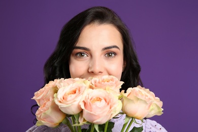 Photo of Young woman with beautiful bouquet on purple background