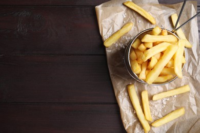Photo of Frying basket with tasty french fries on wooden table, top view. Space for text