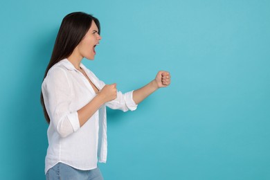 Photo of Aggressive young woman shouting on turquoise background, space for text
