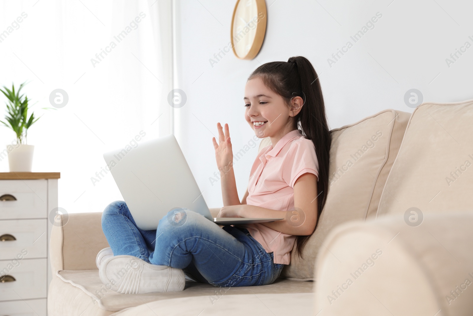 Photo of Little girl using video chat on laptop at home