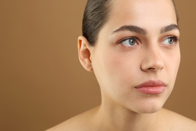 Photo of Young woman with perfect eyebrows on brown background, space for text