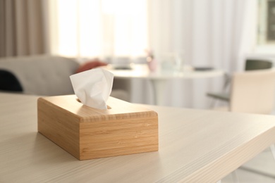 Photo of Wooden napkin holder with paper serviettes on table in room. Space for text