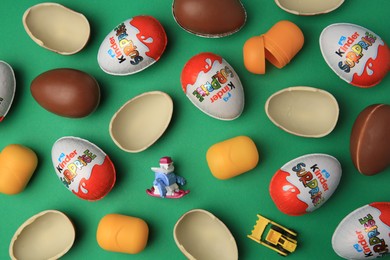 Sveti Vlas, Bulgaria - June 29, 2023: Kinder Surprise Eggs, plastic capsules and toys on green background, flat lay