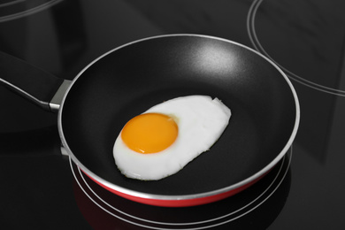 Chicken egg in frying pan on stove, closeup