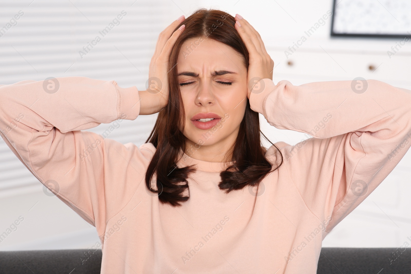 Photo of Young woman suffering from headache indoors. Hormonal disorders