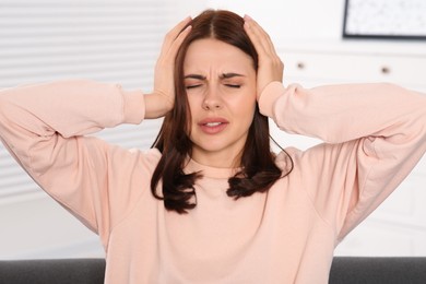 Young woman suffering from headache indoors. Hormonal disorders