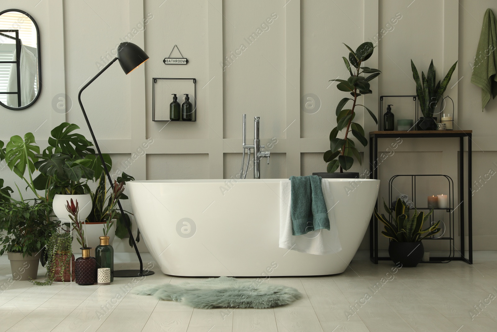 Photo of Stylish bathroom interior with modern tub and beautiful houseplants. Home design