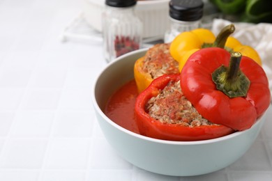 Photo of Delicious stuffed bell peppers on white tiled table. Space for text