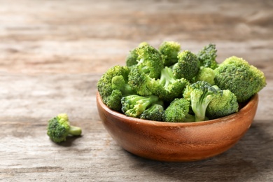 Bowl with fresh green broccoli on wooden table