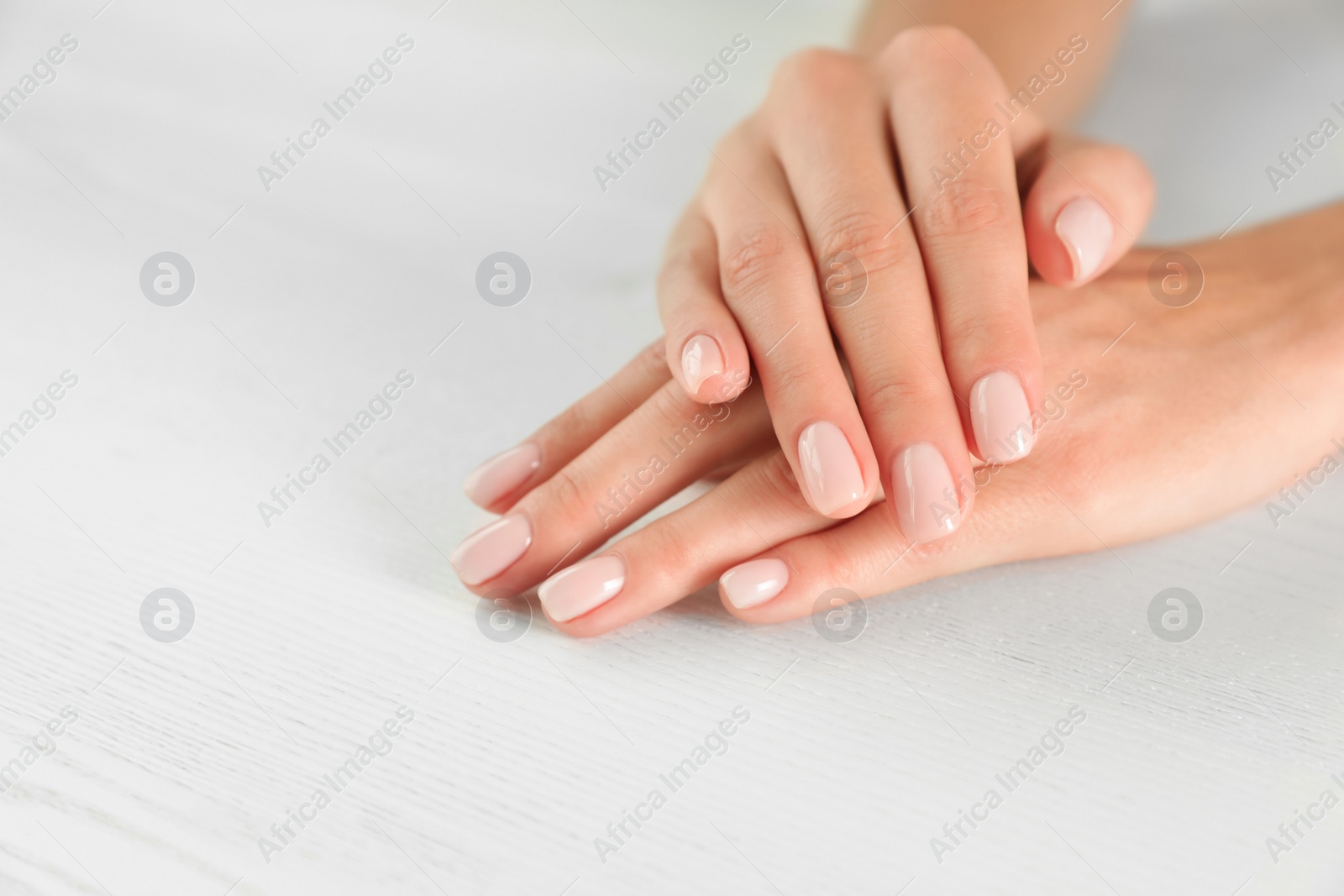 Photo of Closeup view of woman with smooth hands and manicure at table, space for text. Spa treatment