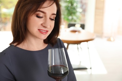 Photo of Woman with glass of wine indoors. Space for text