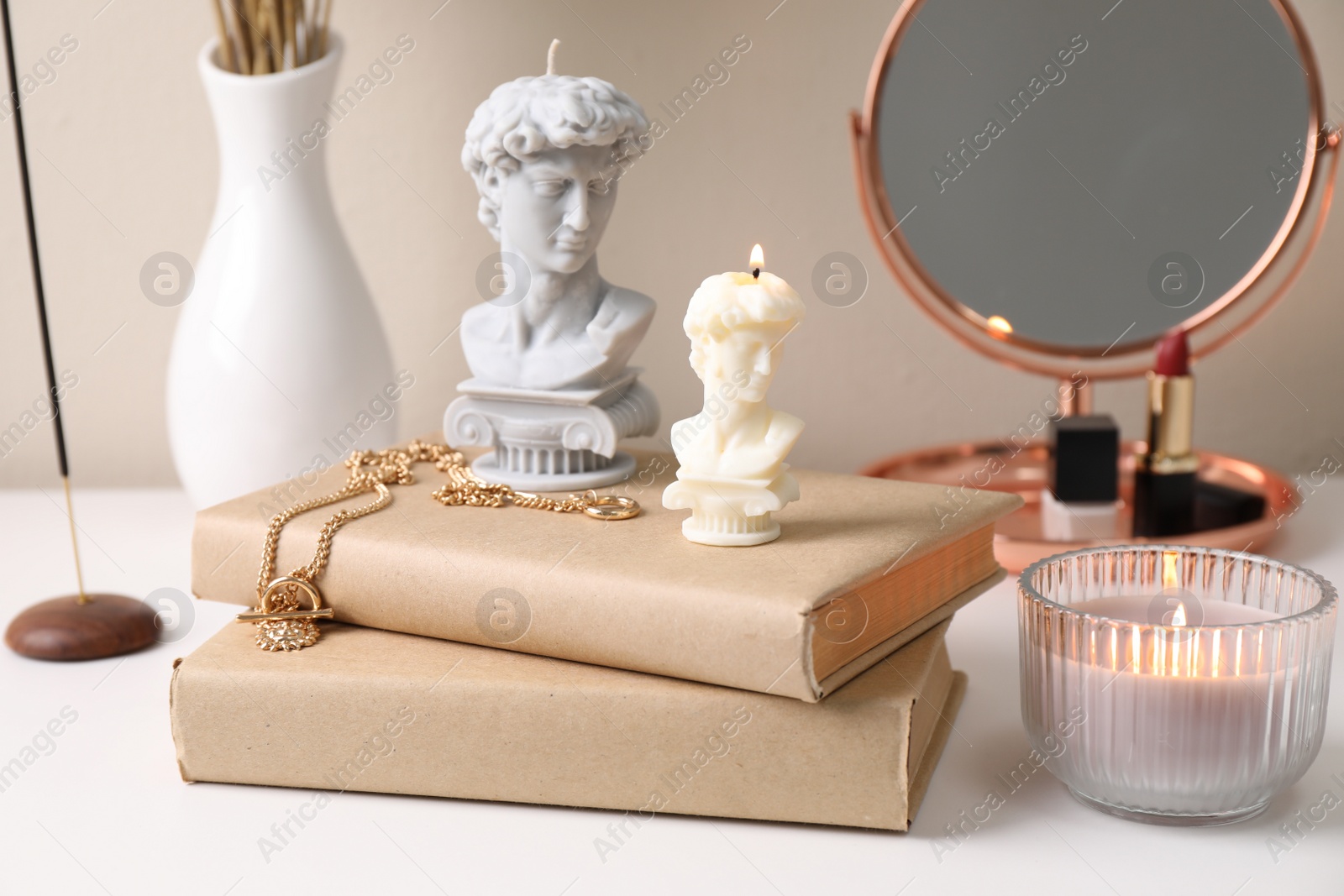 Photo of Beautiful David bust candles and books on white dressing table