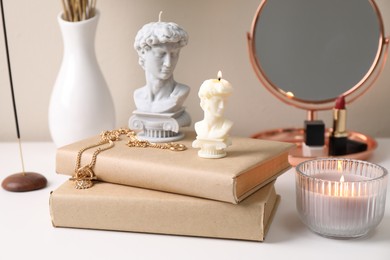 Photo of Beautiful David bust candles and books on white dressing table