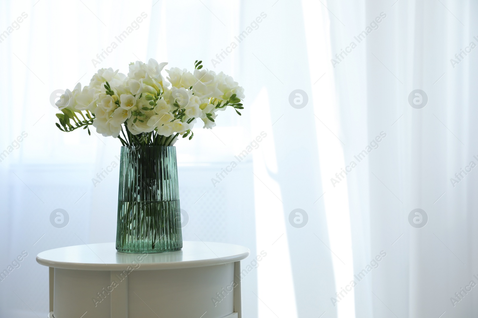 Photo of Beautiful bouquet with fresh freesia flowers on table indoors. Space for text